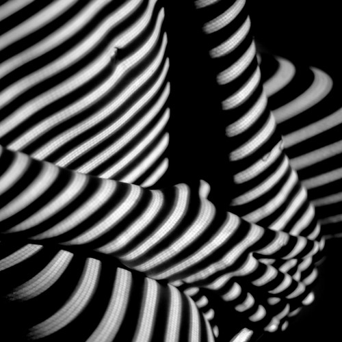 Abstract black and white image focusing on striped shadows creating depth and intrigue.